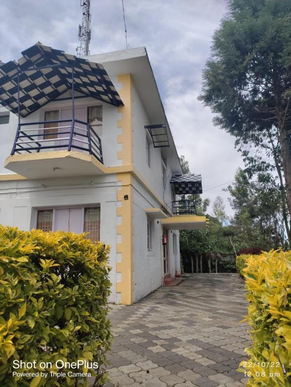 a white and yellow house with a balcony at Belair cottages in Kotagiri