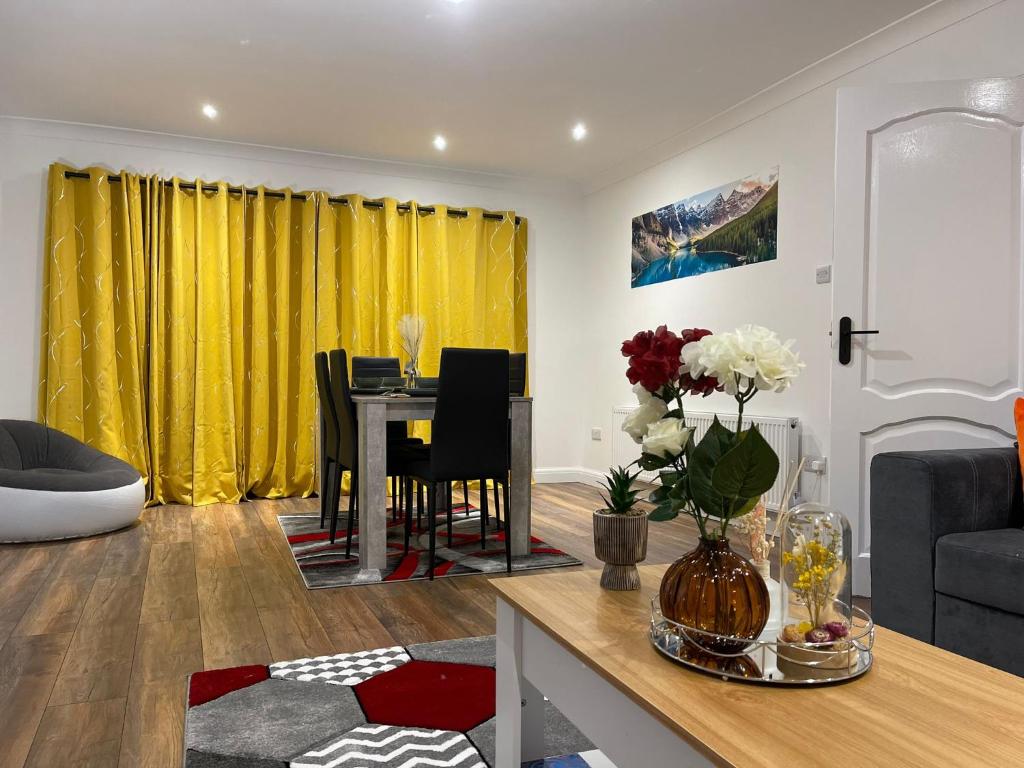 a living room with a table and yellow curtains at The Leckhampton - Company and Family Stays Chester Road in Walsall