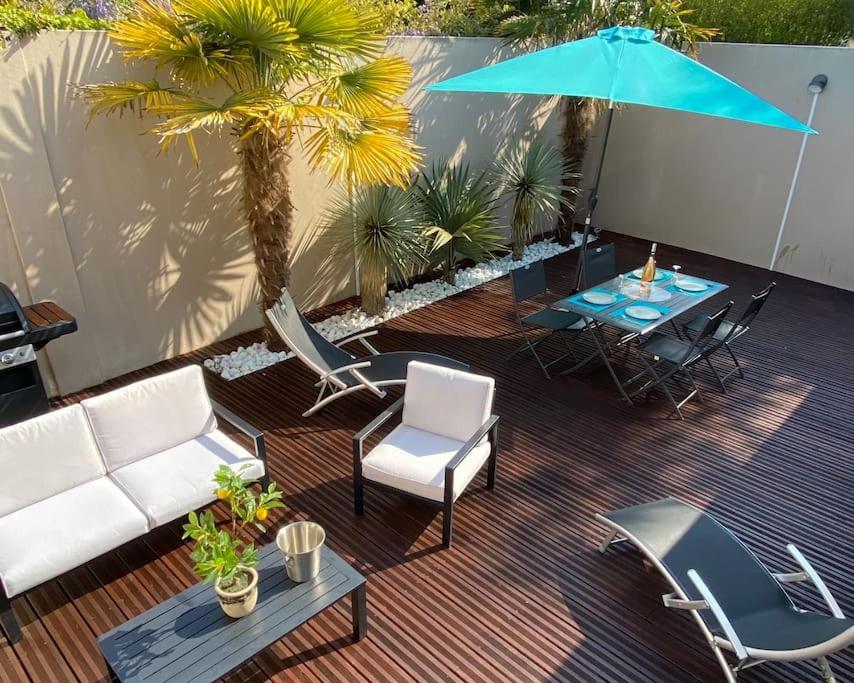 a patio with chairs and a table and an umbrella at Scorfel Lodge, Villa Matisse, Spa & terrasse in Perros-Guirec