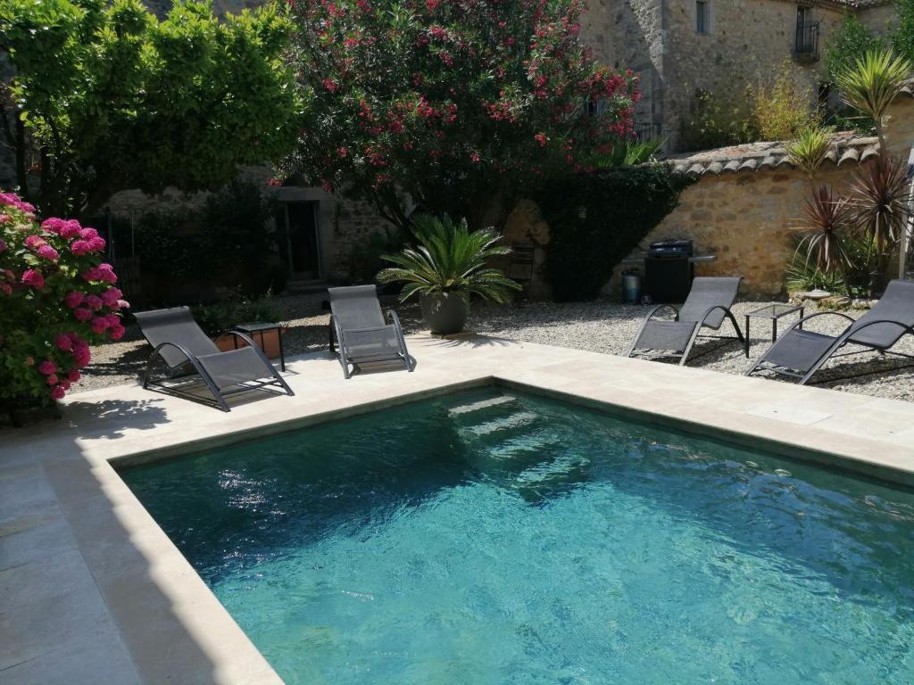 einen Pool mit Liegestühlen und einem Pool in der Unterkunft Gîte de l ancienne Poste in Bourdic