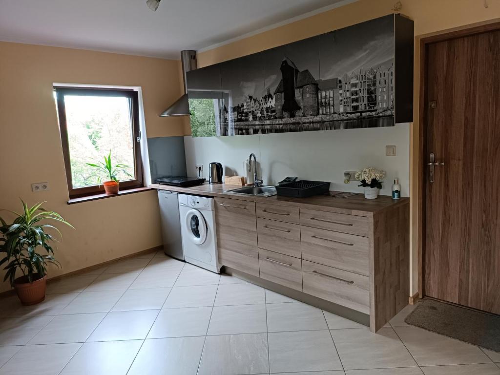a kitchen with a washing machine and a window at Zaścianek Kaszub in Strzebielino