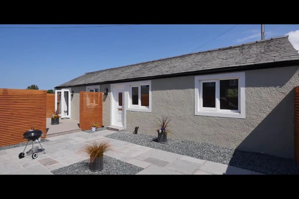 a house with a courtyard with potted plants in front of it at Lake District Coastal cottage in Seascale