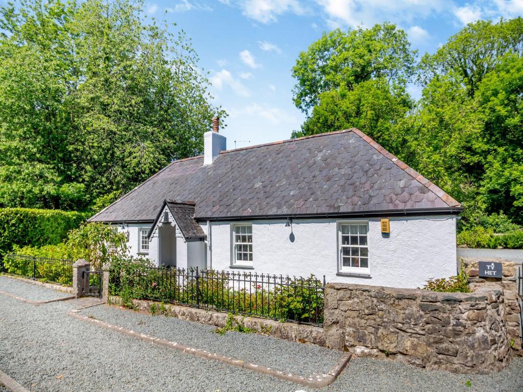 a small white house with a stone fence at Ty Het in Llanfairpwllgwyngyll