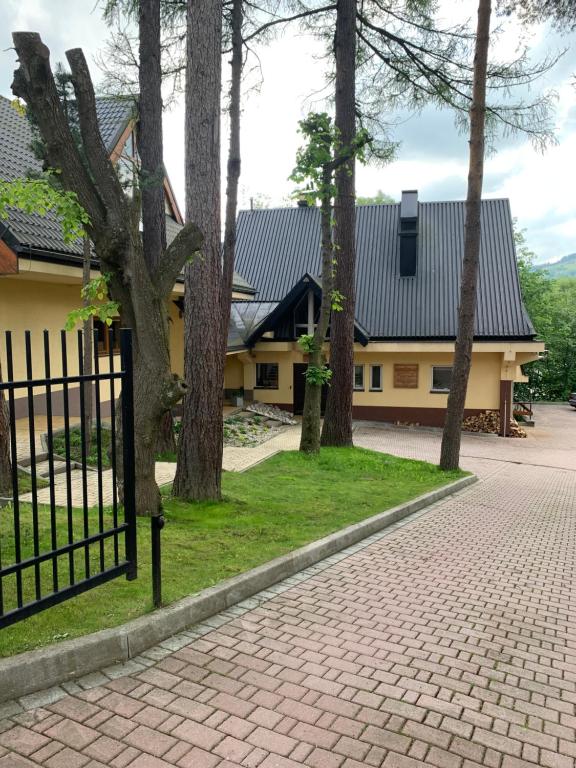a house with a fence and a brick driveway at Pokoje Sunshine World Suites in Zakopane
