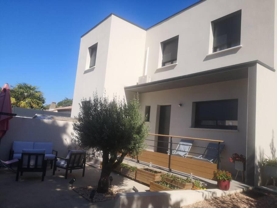 a white house with a table and chairs in front of it at Villa contemporaine à 10mn des plages in Lattes