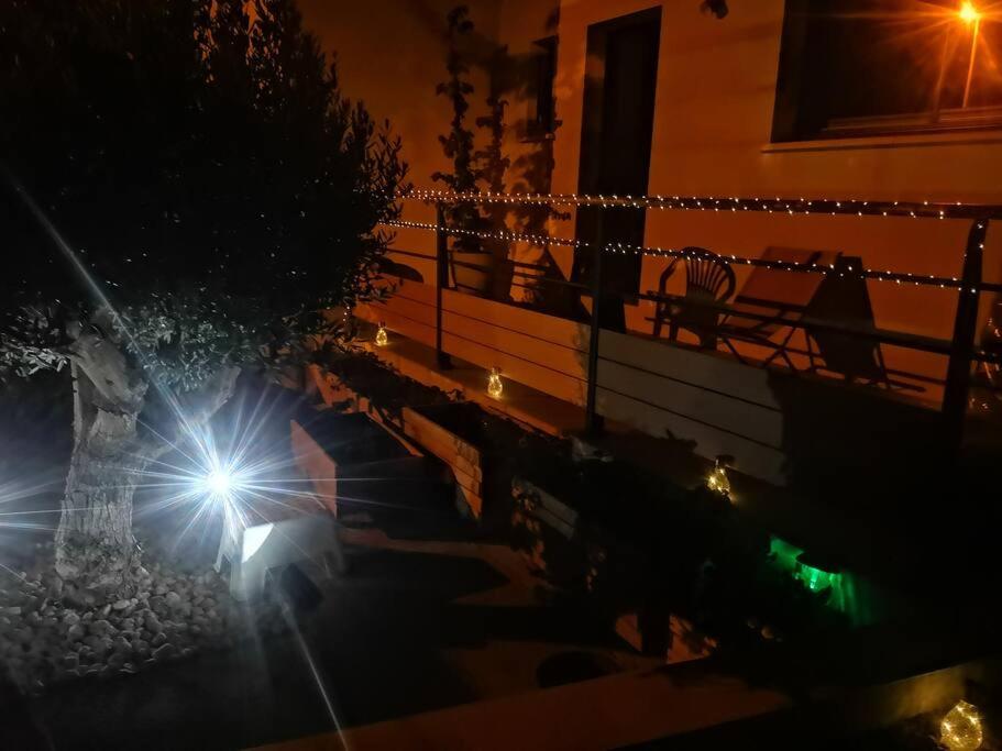 a person sitting on a porch at night with lights at Villa contemporaine à 10mn des plages in Lattes