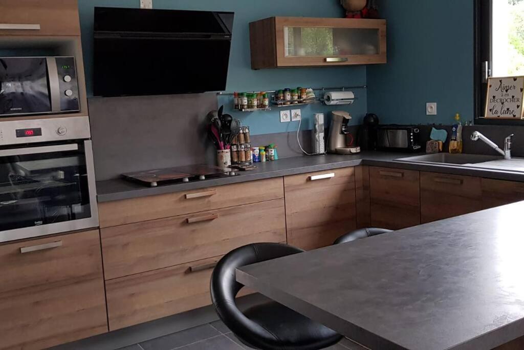 a kitchen with wooden cabinets and a table and a microwave at Villa contemporaine à 10mn des plages in Lattes