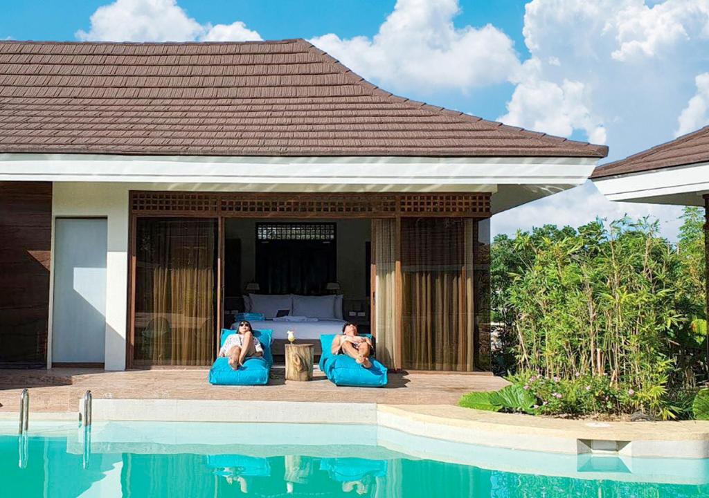 two people sitting on blue chairs next to a swimming pool at Tag Resort in Coron