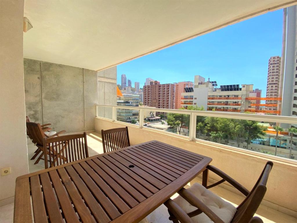 a balcony with a wooden table and chairs and a large window at Gemelos 22-1-5 in Benidorm