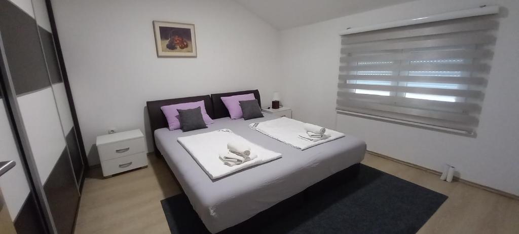 a bedroom with a bed with two pillows and a window at Apartments Platz in Mostar