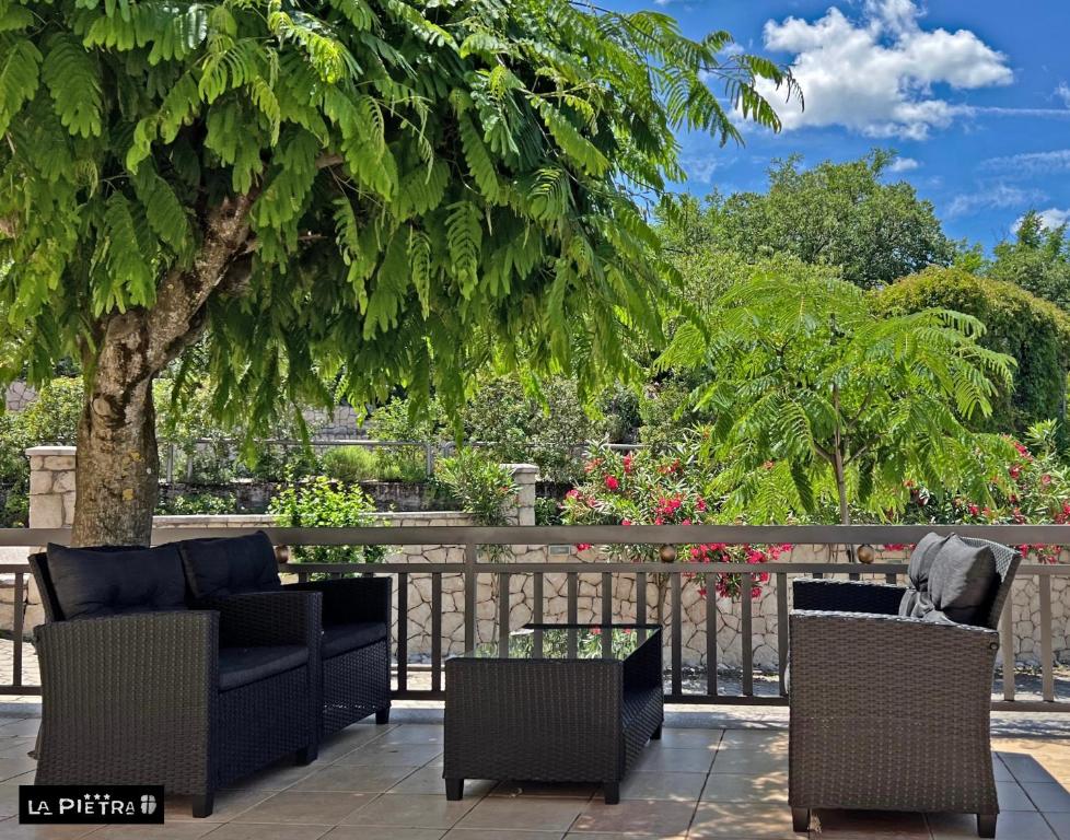 un patio con un sofá, sillas y un árbol en La Pietra Family Hotel, en Međugorje