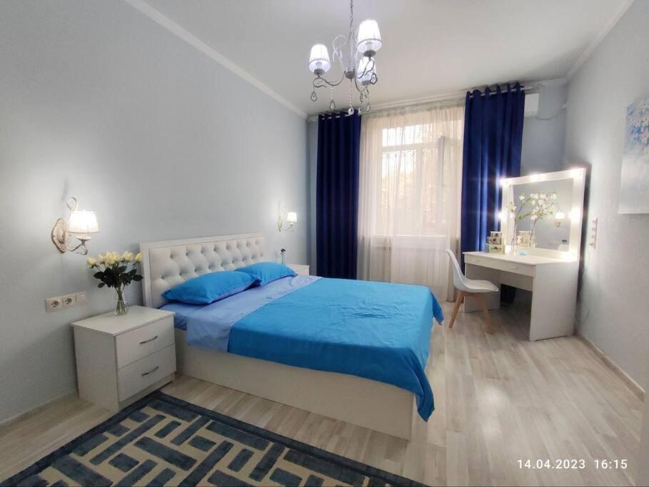 a bedroom with a blue bed and a desk at Стильный уют в центре in Almaty