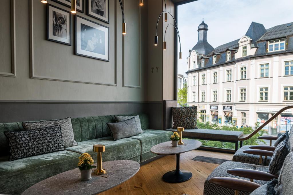 a living room with a green couch and a large window at MIANO Hotel & Bar in Munich