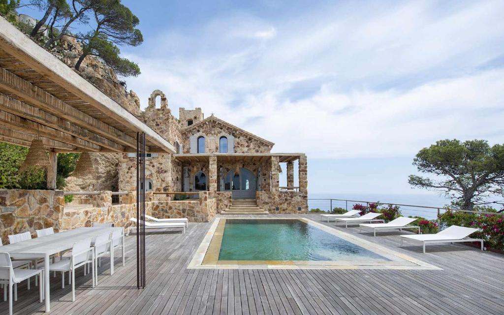 Villa con piscina y sillas en Villa San Jaume Apostol Luxury, en Tossa de Mar