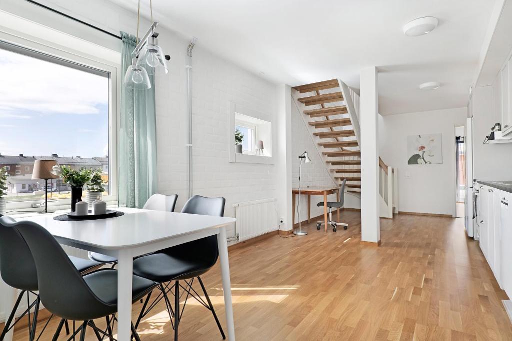 una cucina e una sala da pranzo con tavolo e sedie bianchi di Guestly Homes - 3BR City Charm a Piteå