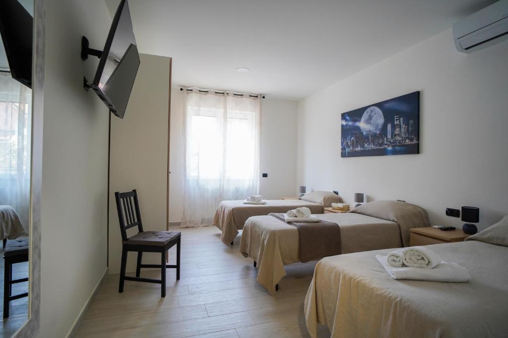 a hotel room with three beds and a window at Bnbook-Borromeo 4 Fiera Milano Rho in Rho