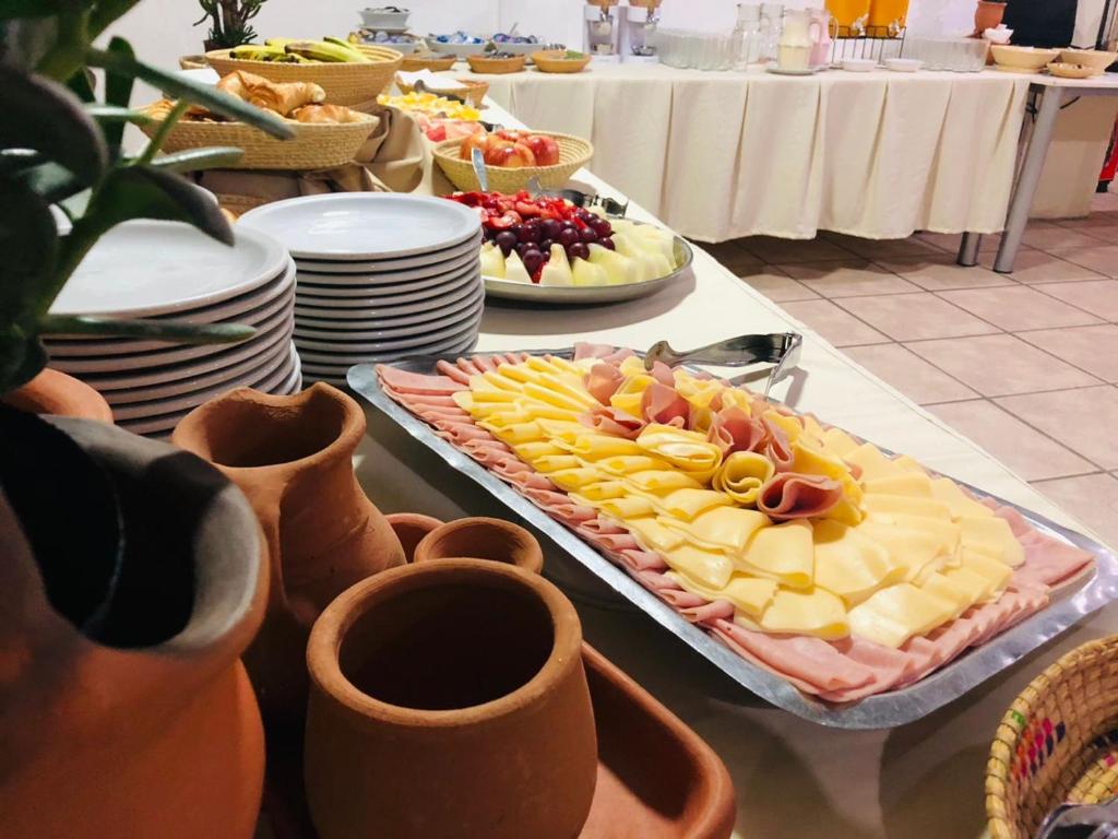 a table topped with a tray of cheese and fruit at Grand Hotel by MH in Termas de Río Hondo