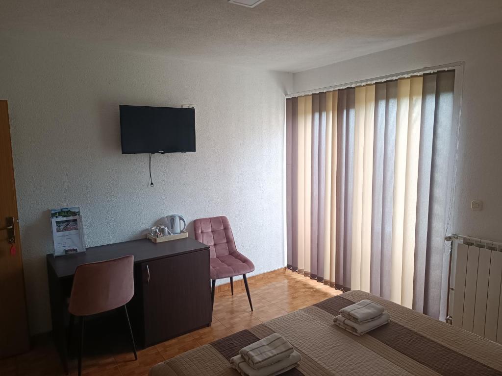 ein Hotelzimmer mit einem Schreibtisch und einem TV an der Wand in der Unterkunft Rooms Marijanović Plitvice in Vrelo Koreničko