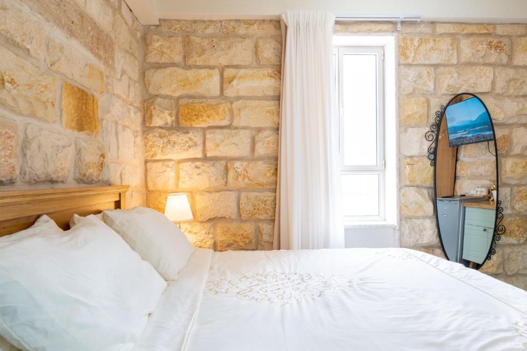 a bedroom with a white bed and a stone wall at Via Maria Boutique Suites In The Middle Of The city in Haifa