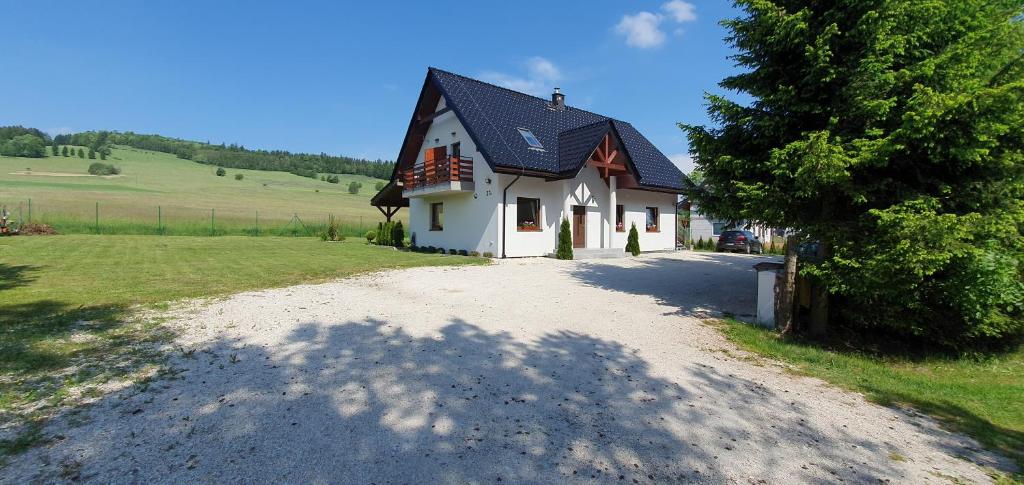 a white house with a black roof on a road at Pokoje Przy Polanie in Stronie Śląskie