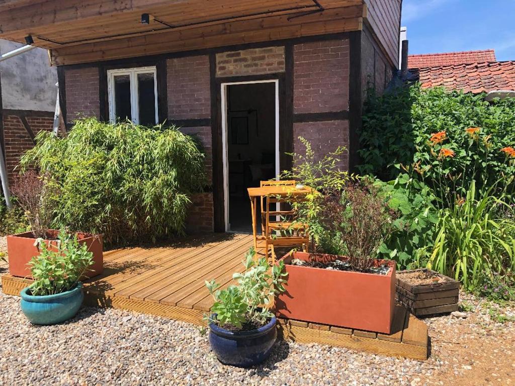 una terraza de madera con macetas de plantas frente a una casa en La chambre de l'abreuvoir, en Bergicourt