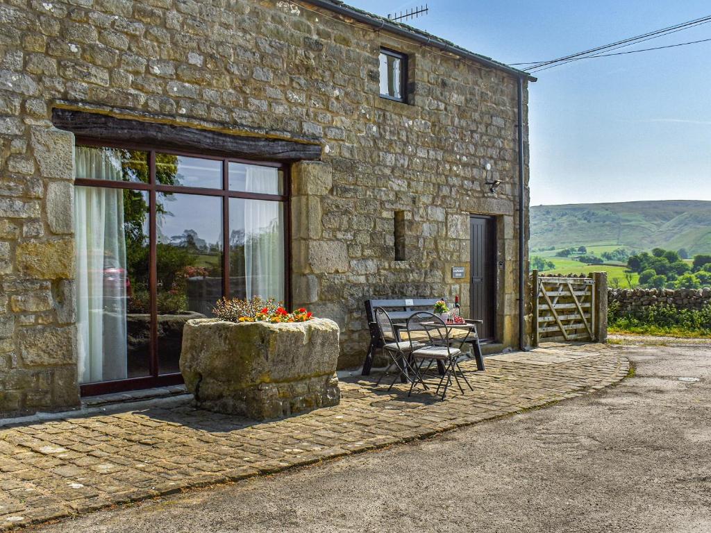 a stone house with a table and chairs outside at Ladycroft House in Hebden