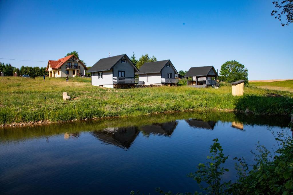 a row of houses next to a body of water at Chatki Dwa Żurawie in Wiżajny