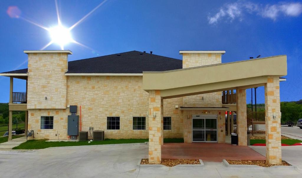 un grand bâtiment en briques avec le soleil au ciel dans l'établissement Westwood Inn & Suites, à Gonzales