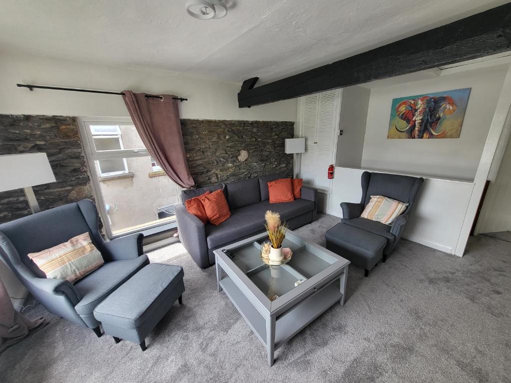 a living room with a couch and chairs and a table at Courtyard Cottage in Cartmel
