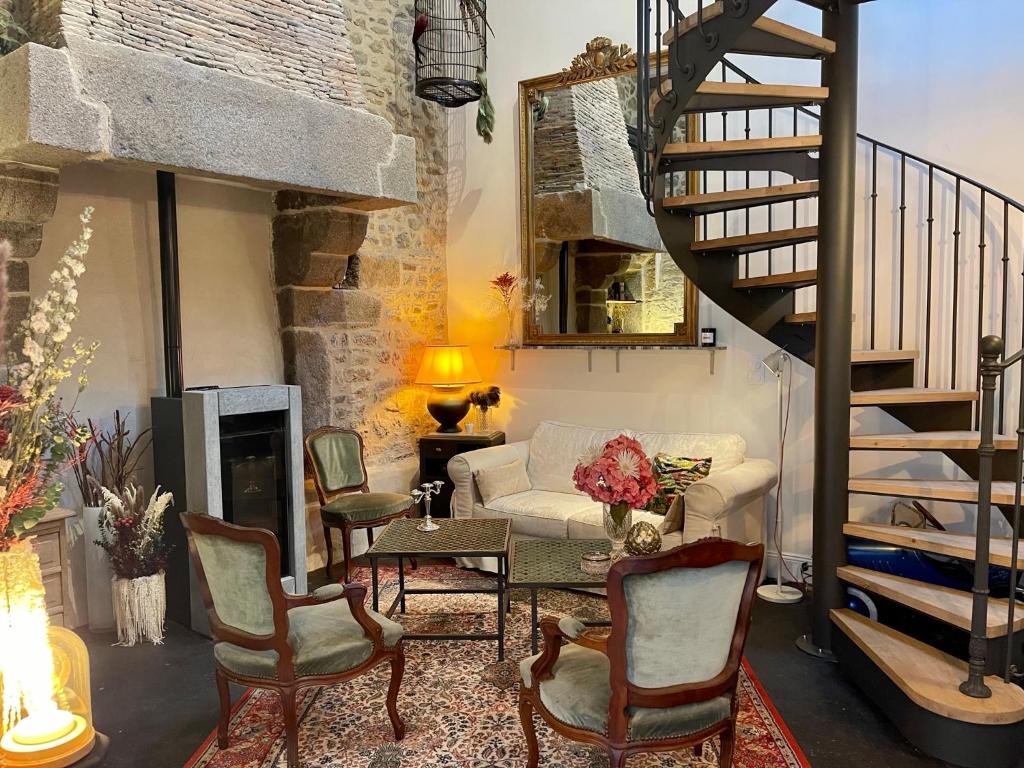 a living room with a staircase and a couch and chairs at Petit gîte d’arrière-cour au pied du Château in Combourg