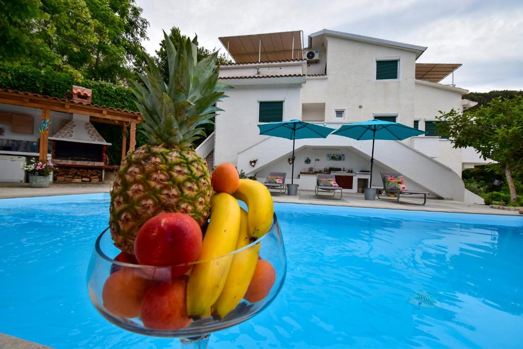 a bowl of fruit sitting next to a swimming pool at Villa Kristina Rab in Supetarska Draga