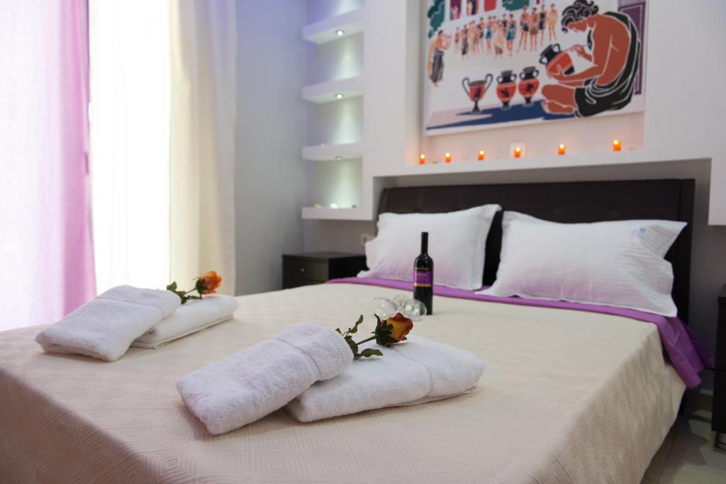 Anemi Leros Apartments في Panteli: سرير مع مناشف وزجاجة من النبيذ عليه