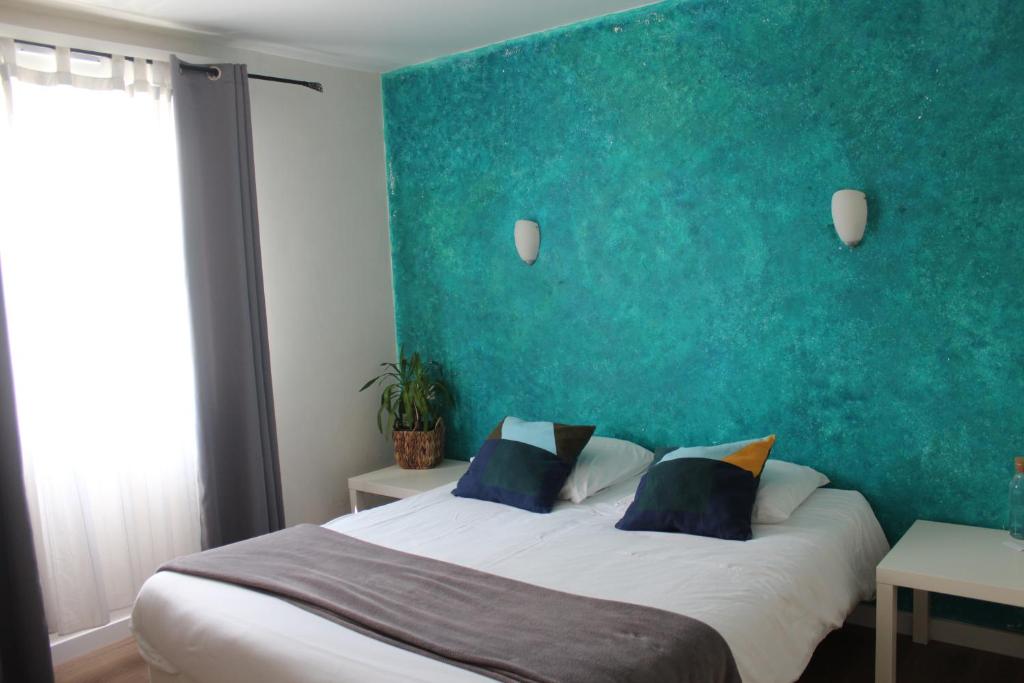 een slaapkamer met een groot bed met een groene muur bij Les Bruyeres in Plélan-le-Grand