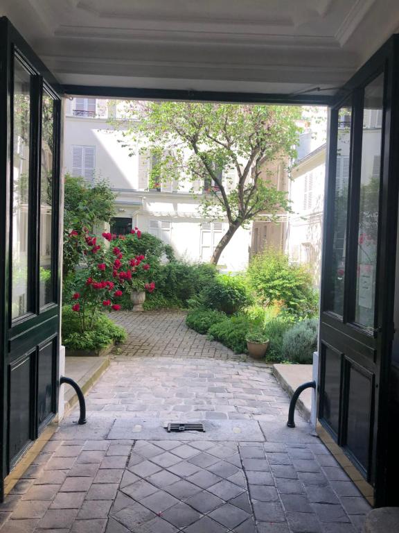 une porte ouverte donnant sur une cour fleurie. dans l'établissement Charming Relais Poste 17ème, à Paris