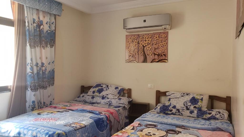 a bedroom with two beds and a air conditioner on the wall at Stanley Bridge apartment Alexandria in Alexandria