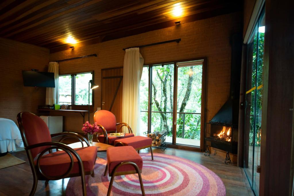 a living room with a table and chairs and a fireplace at Pousada Tijupá in Visconde De Maua