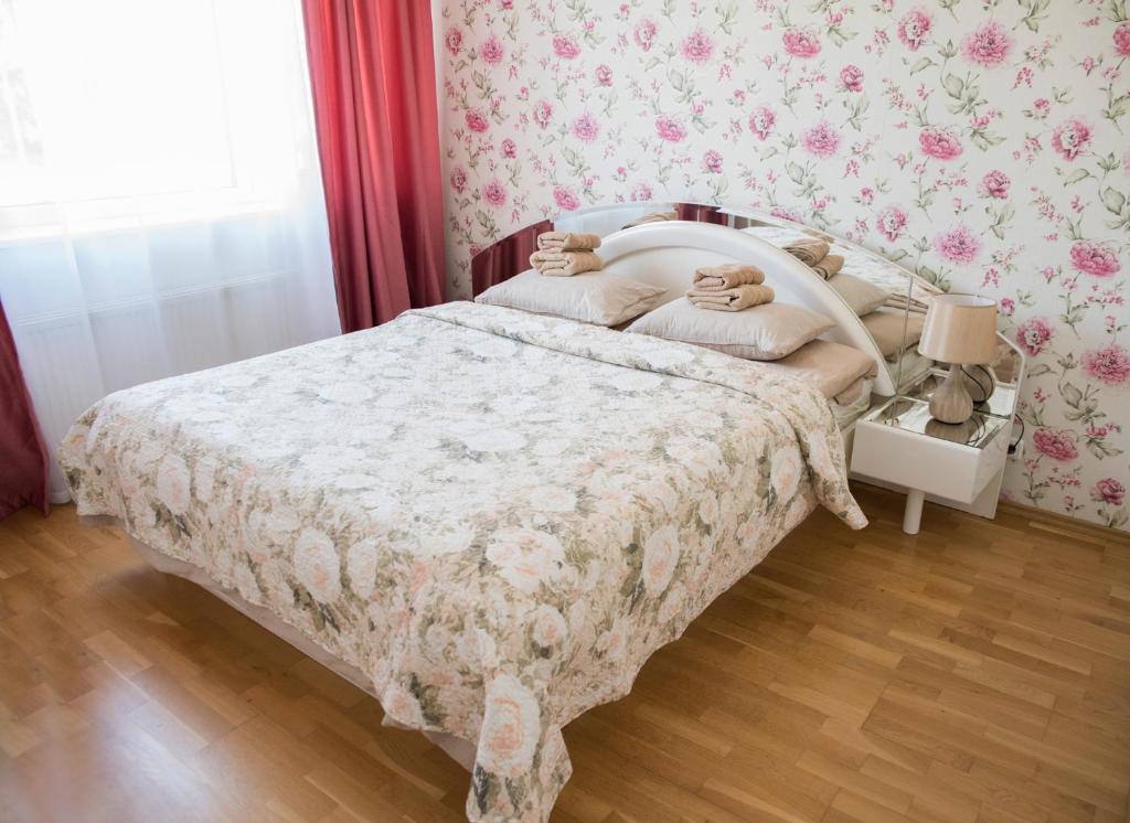 een slaapkamer met een bed met bloemenbehang bij Aleksandria Apartment in Pärnu