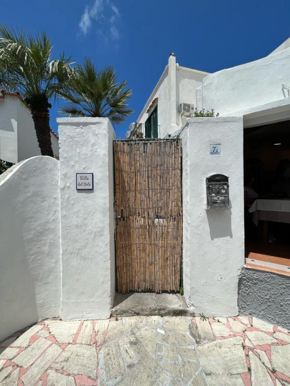 a white building with a wooden gate and palm trees at Villa del Sole in Capri