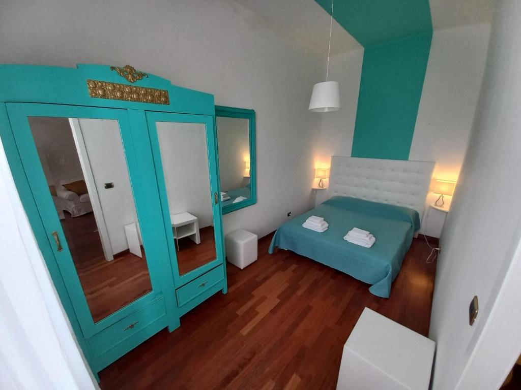 Habitación pequeña con cama azul y espejo. en Sole amarè guest house, en Bari
