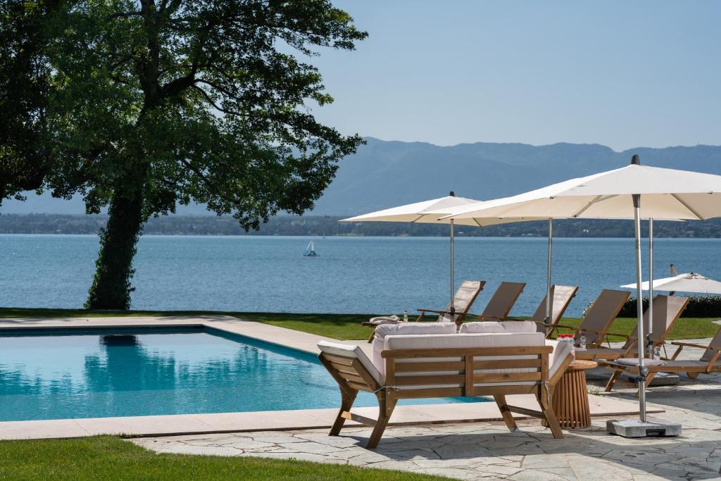 - une table et des chaises avec des parasols à côté de la piscine dans l'établissement Park Villa Geneva - Swiss Hotel Apartments, à Genève