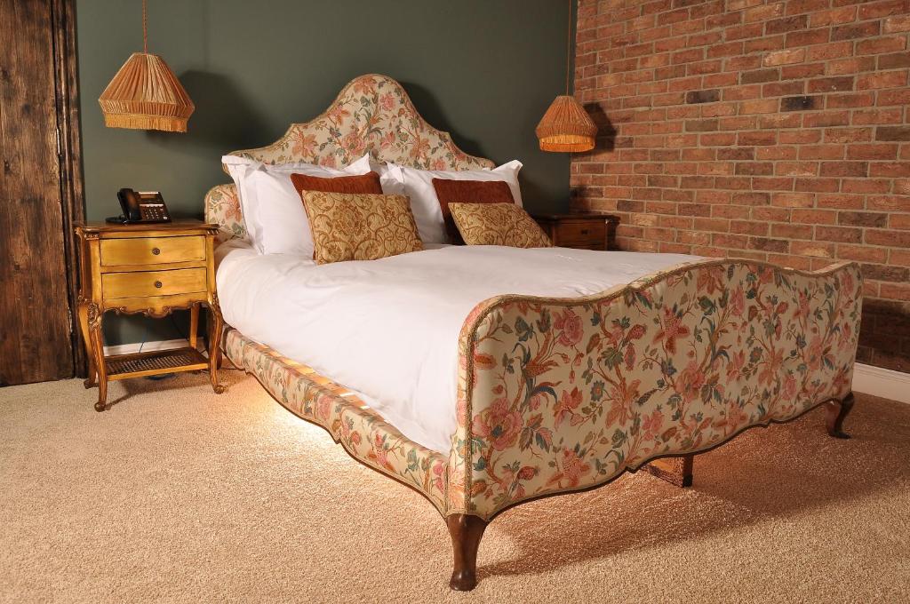a bedroom with a bed and a couch and a brick wall at The Joiners Arms in Chathill