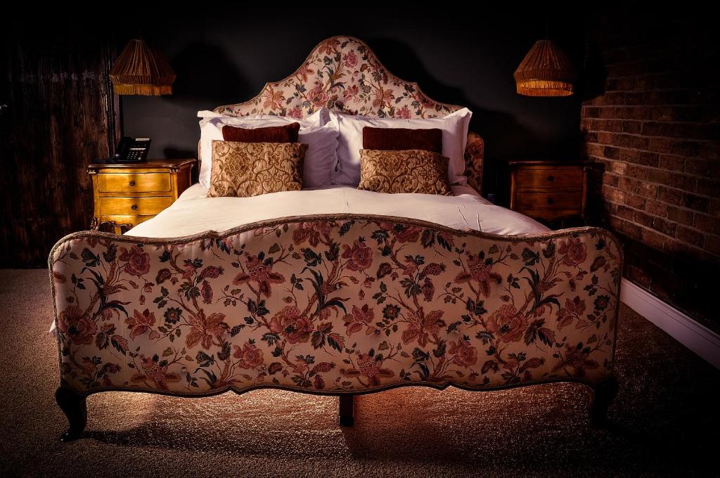 a bed with a floral bedspread and pillows on it at The Joiners Arms in Chathill