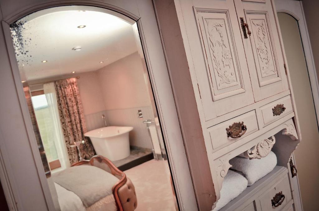 a bathroom with a mirror and a sink and a tub at The Joiners Arms in Chathill