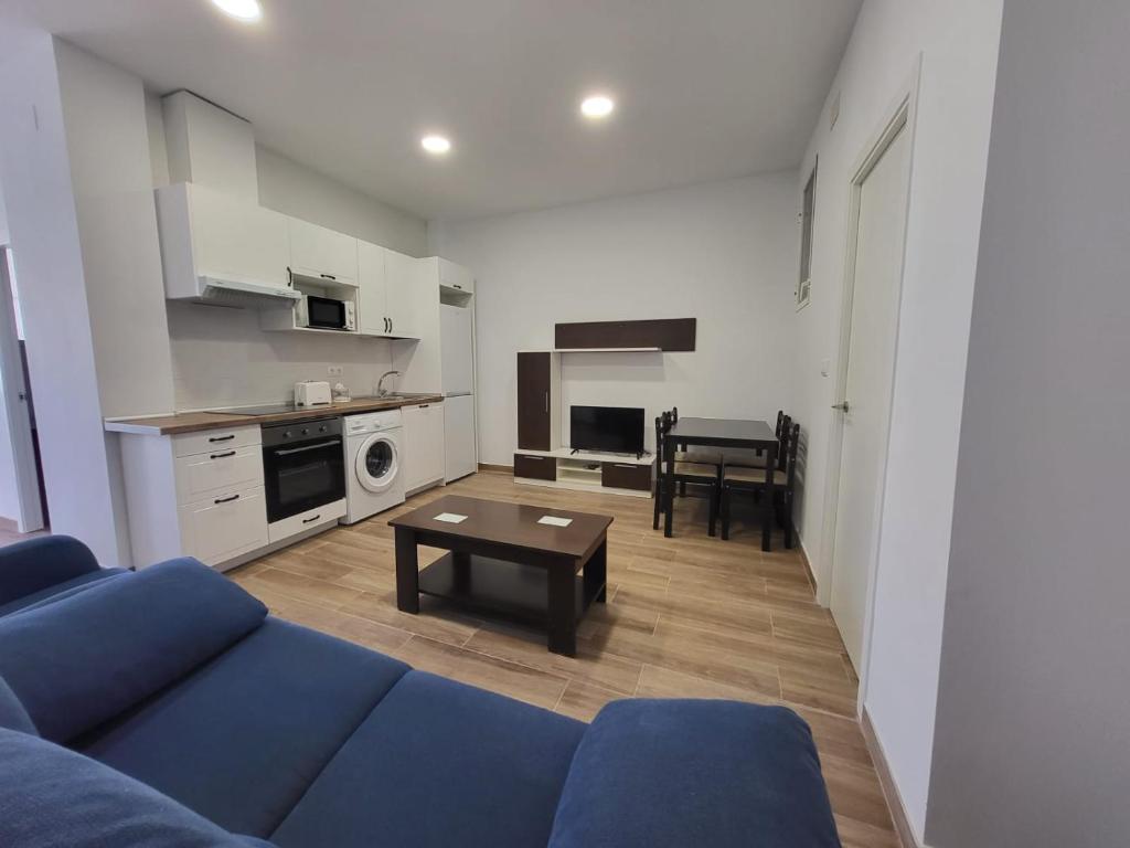 ein Wohnzimmer mit einem blauen Sofa und einem Tisch in der Unterkunft Apartamento Parque Bahía in Puerto Real