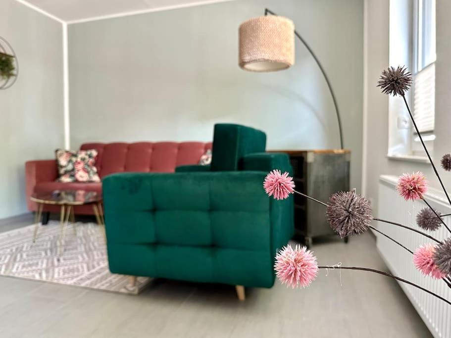 a green chair in a living room with a couch at Ferienwohnung komfortabel Wohnen Bremerhaven in Bremerhaven