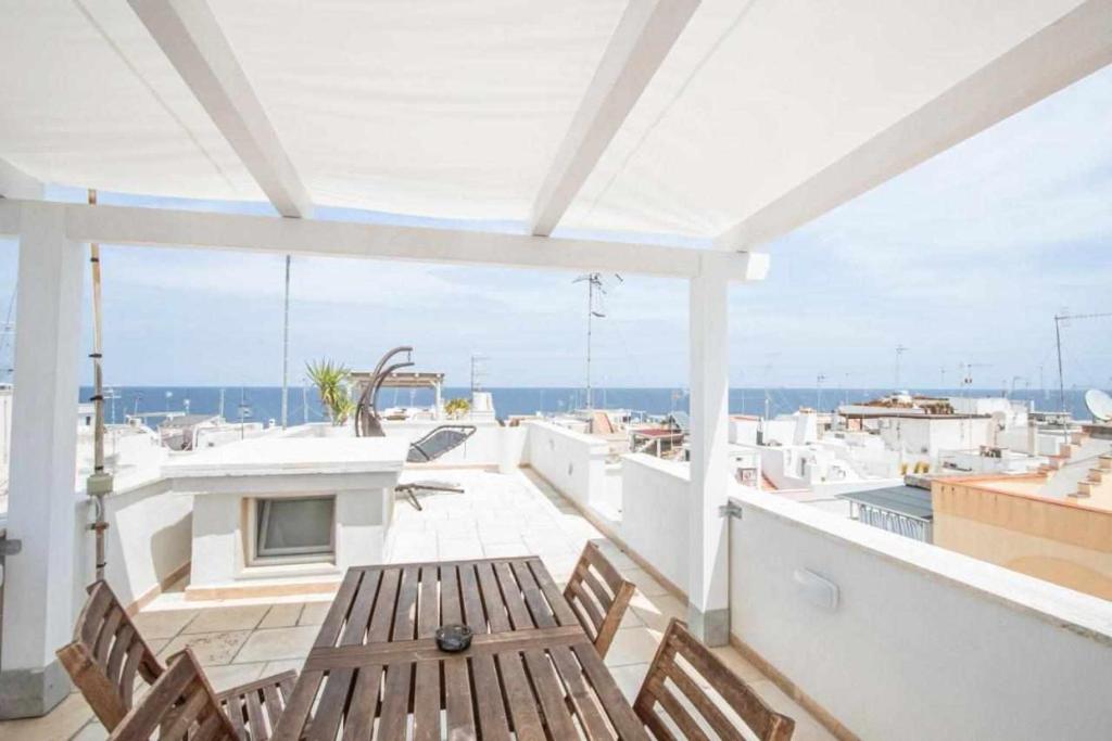 een patio met een houten tafel en stoelen op een balkon bij Verde a Mare in Polignano a Mare