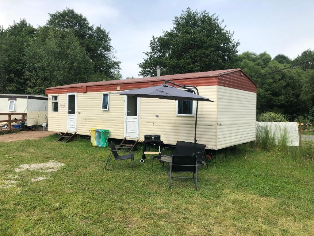 een caravan met een tafel en stoelen en een paraplu bij Stawy Zielona Dolina in Kudowa-Zdrój