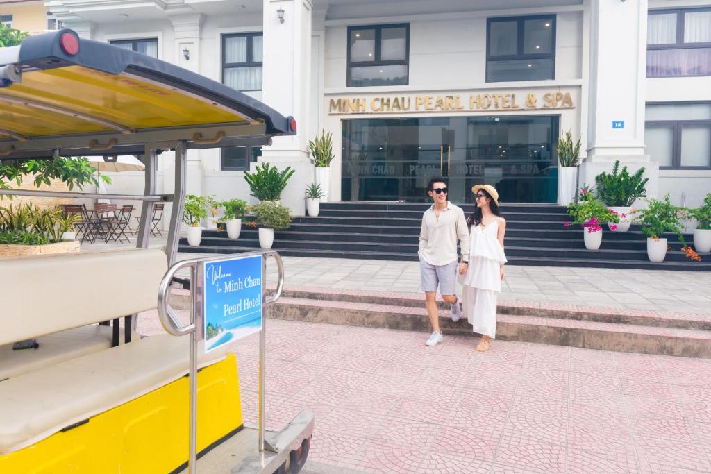 Ein Mann und eine Frau stehen vor einem Gebäude in der Unterkunft Minh Chau Pearl Hotel & Spa - Quan Lan Island in Provinz Quang Ninh