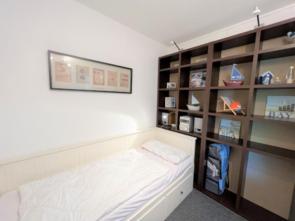 ein Schlafzimmer mit einem Bett und einem Bücherregal in der Unterkunft Panoramic App A03-1 in Sierksdorf