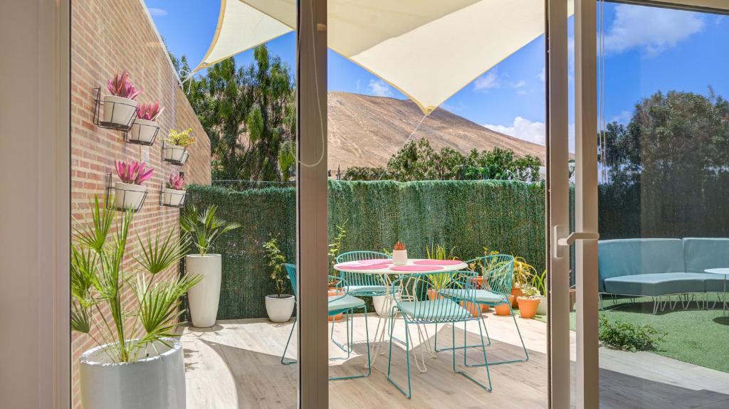 un patio con mesa y sillas y un jardín en Casa MIMAR - moderna, jardín y wifi fibra 1 GB, ideal para vacaciones y teletrabajo, en La Oliva